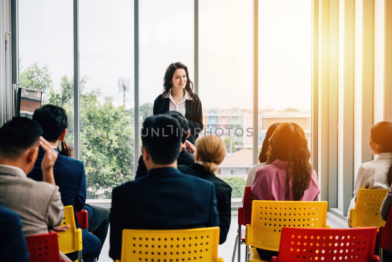 In an office meeting, a diverse group of professionals communicates effectively. Managers, standing and listening, lead discussions while their team members sit, engaged and cooperative. by Sorapop