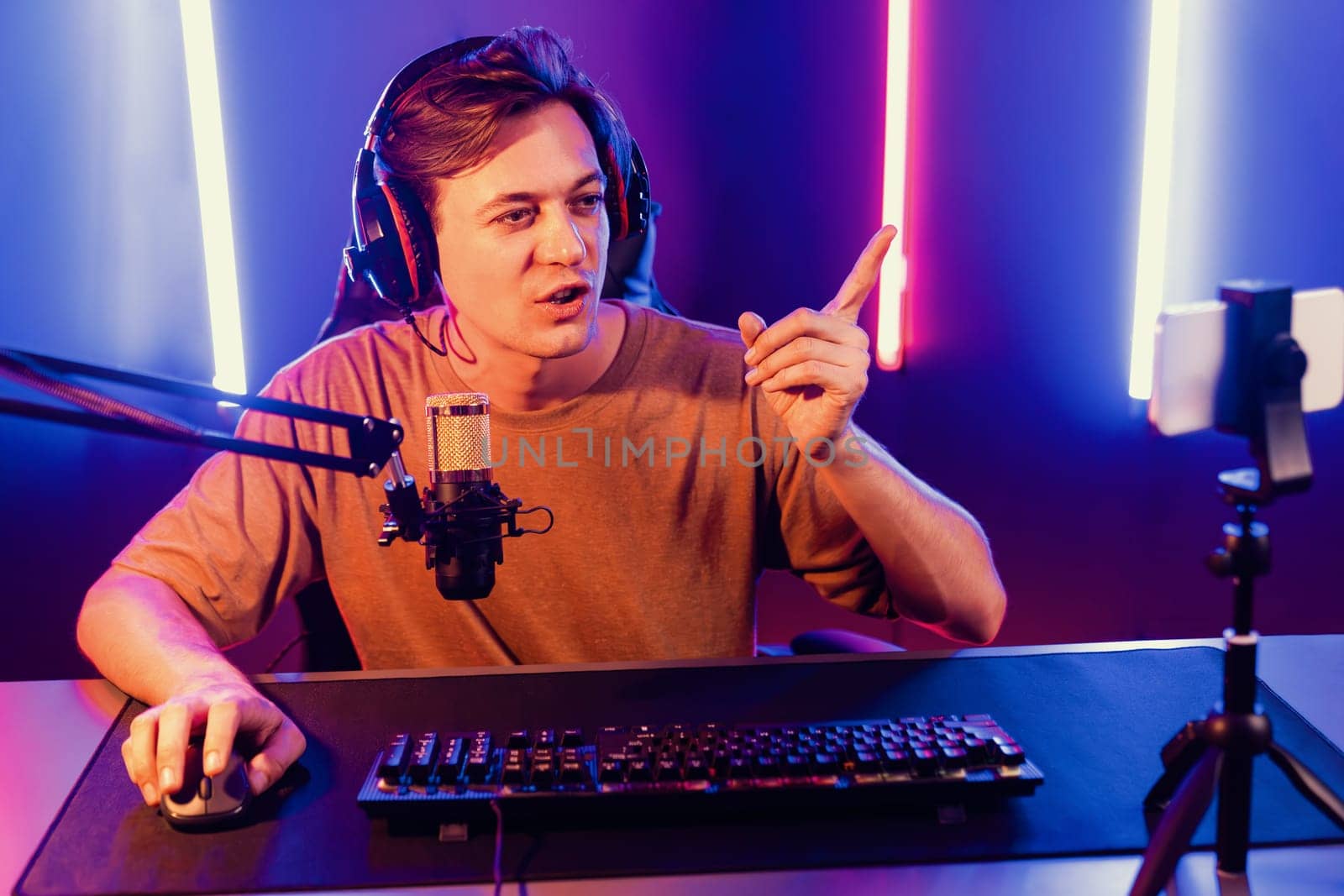 Host channel of gaming smart streamer playing online game to be winner, wearing headphone with viewers live steaming on media social online for selected team competition at neon light room. Pecuniary.