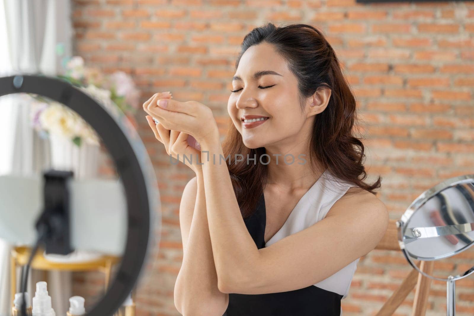 Asian Woman influencer shoot live streaming vlog video review makeup uttermost social media or blog. Happy young girl with cosmetics studio lighting for marketing recording session broadcasting online