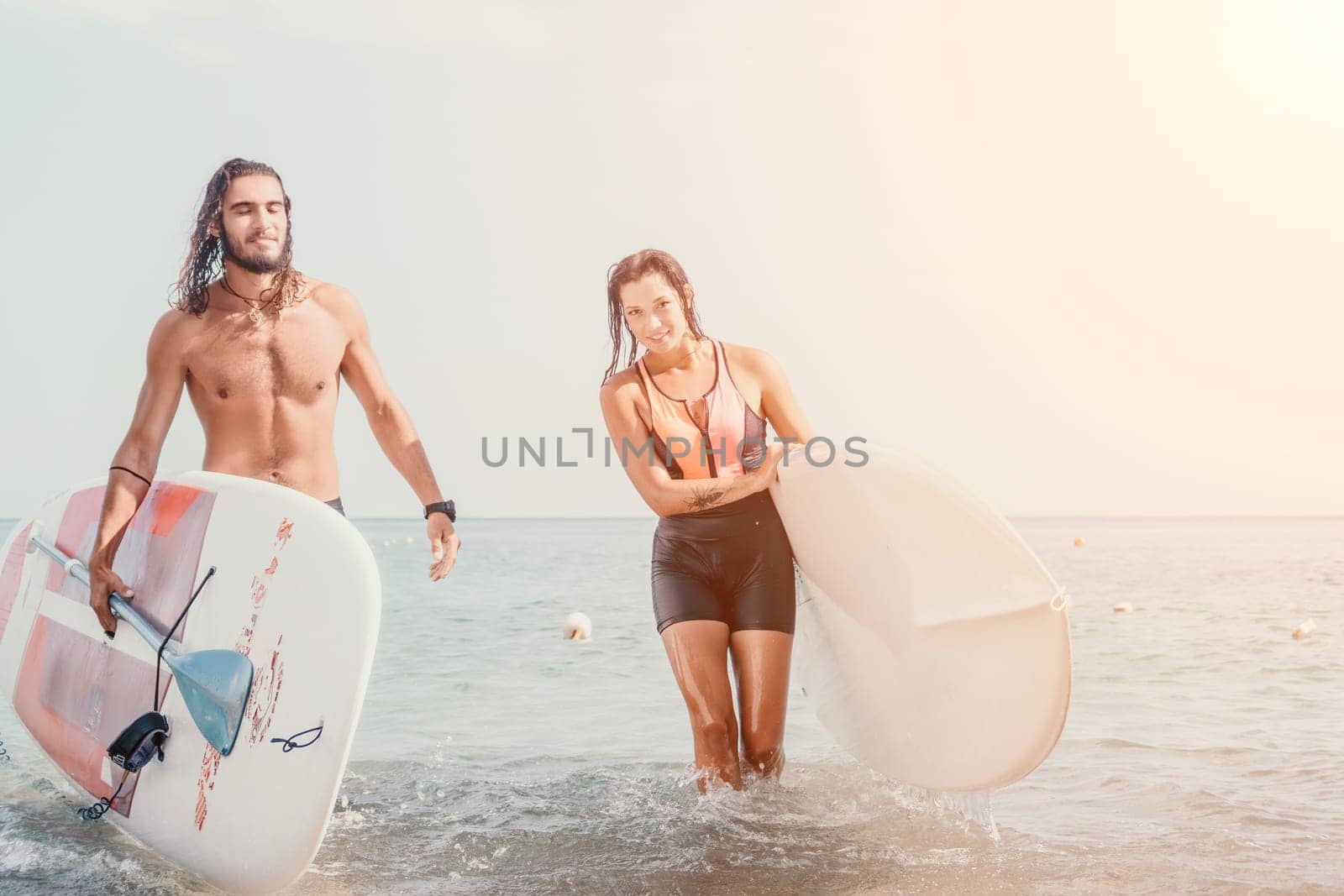 Woman man sea sup. Close up portrait of beautiful young caucasian woman with black hair and freckles looking at camera and smiling. Cute woman portrait in a pink bikini posing on sup board in the sea by panophotograph