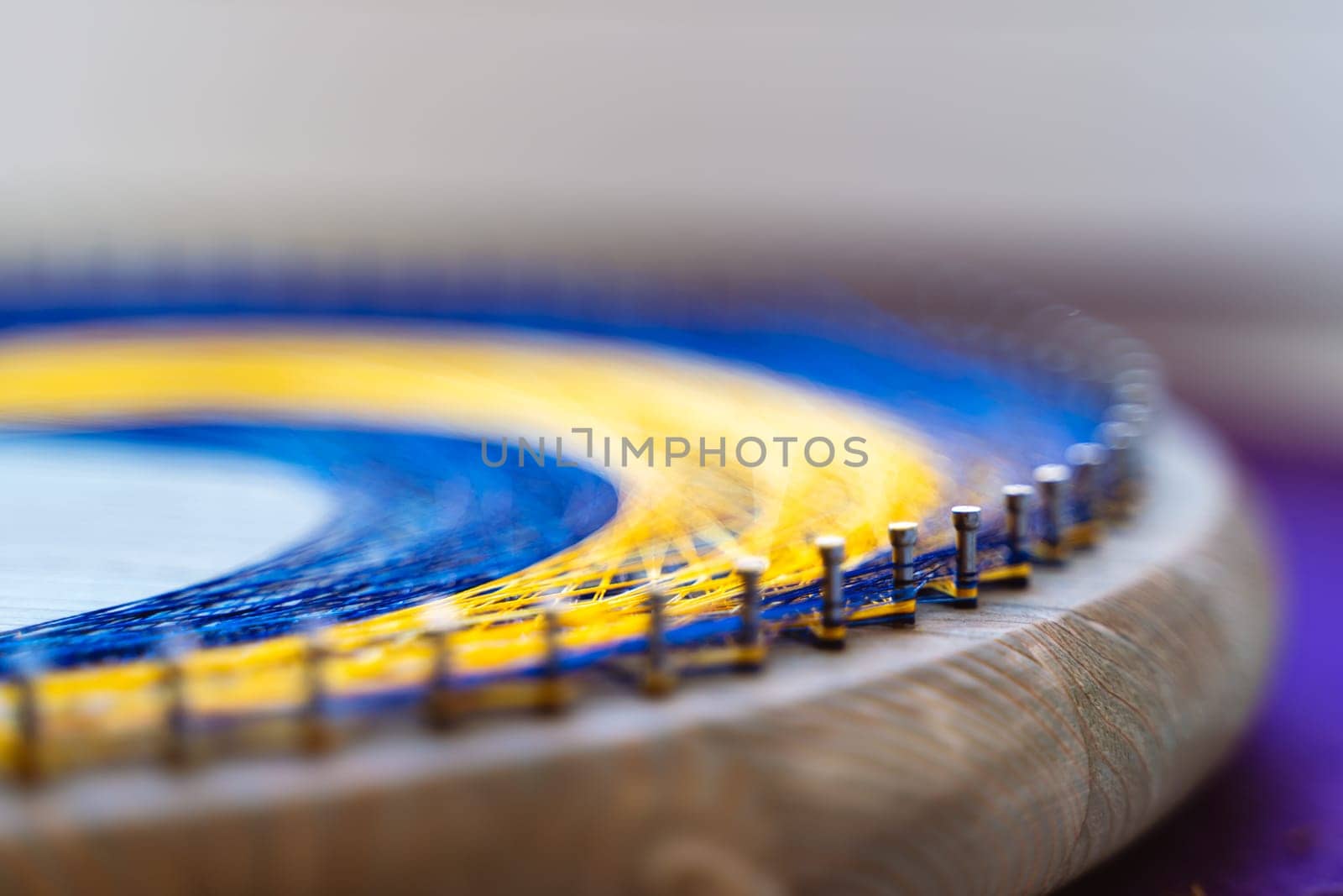 Colored thread mandala on a wooden board with nails. Mandala Moon Harmony Sun esotericism and psychology pictures from yellow and blue silk threads