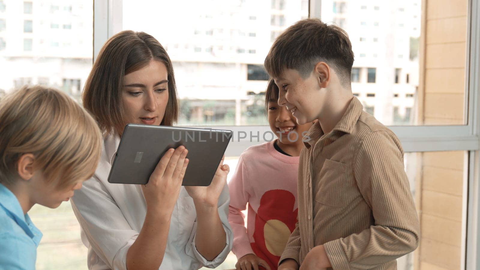 Smart teacher holding tablet while open online lesson to group of students. Skilled instructor explained engineering code lesson while young learner sitting and listening presentation. Erudition.