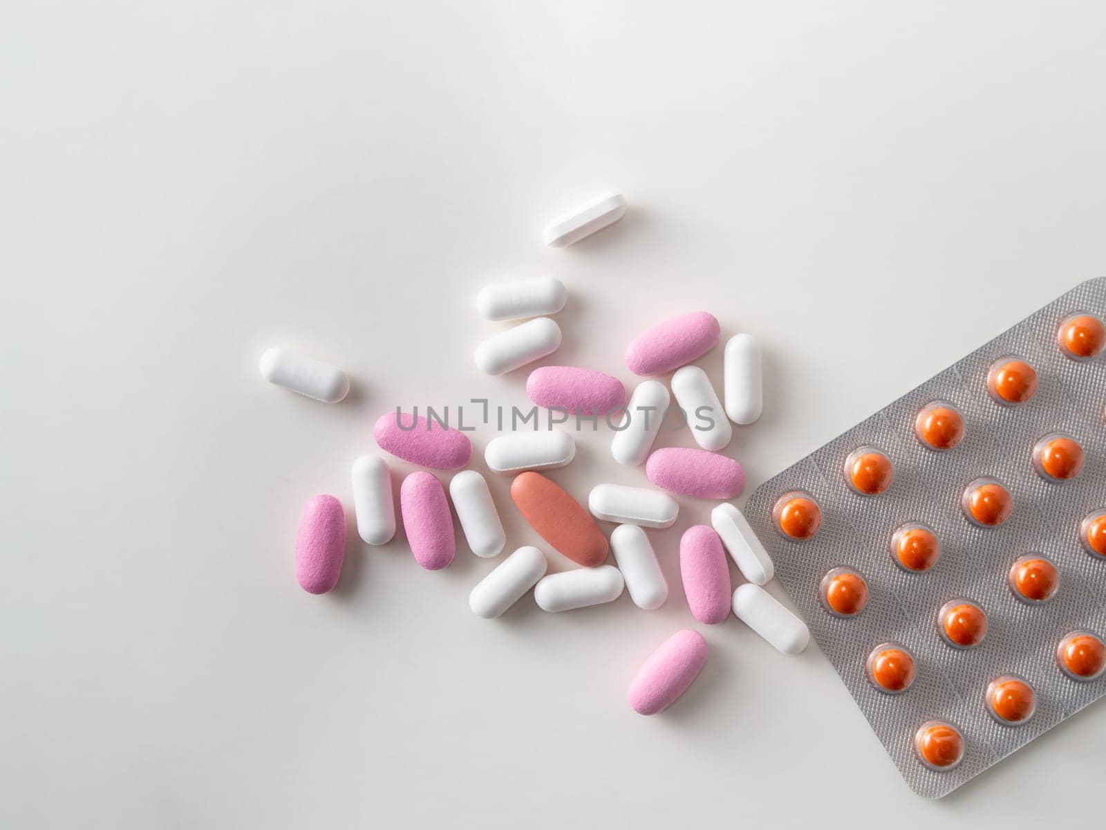 multicolored medical pills and packs of pills on a white table.