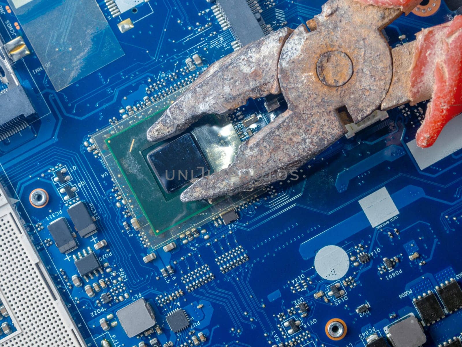 Computer repair concept. Old rusty passages on a blue laptop motherboard. The concept of unskilled work