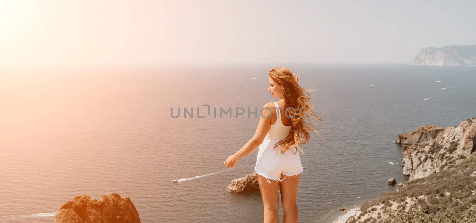 Woman travel sea. Young Happy woman in a long red dress posing on a beach near the sea on background of volcanic rocks, like in Iceland, sharing travel adventure journey