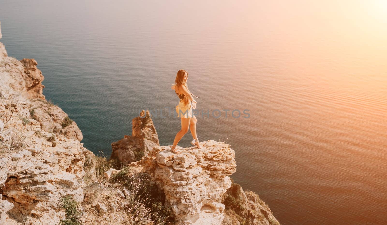 Woman travel sea. Happy tourist taking picture outdoors for memories. Woman traveler looks at the edge of the cliff on the sea bay of mountains, sharing travel adventure journey.