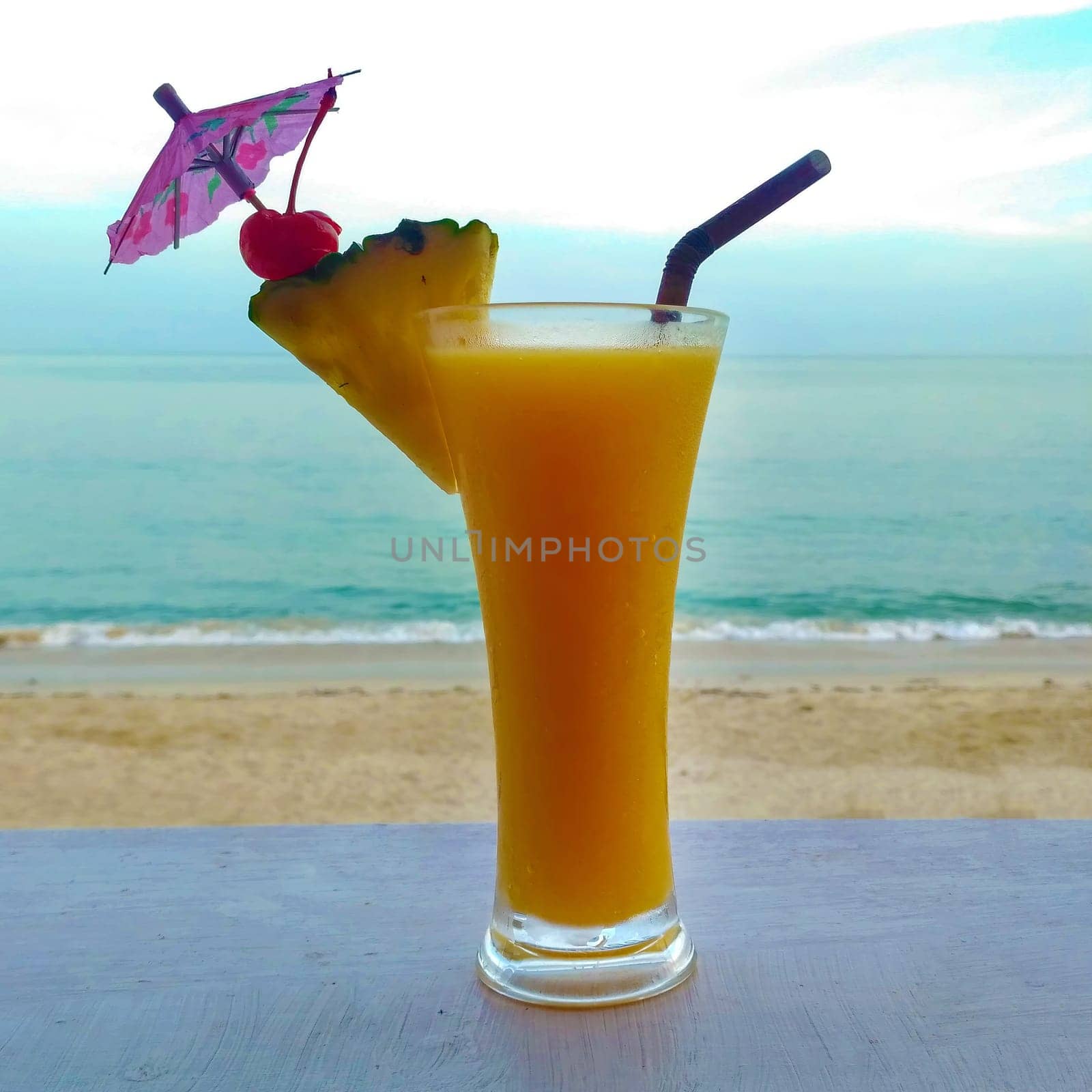 Fresh orange cocktail on wooden table. Blur beach on background by Andre1ns