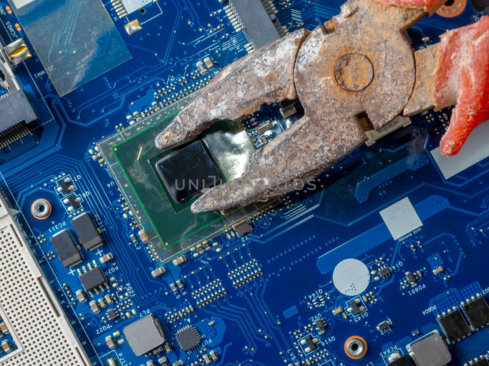 Computer repair concept. Old rusty passages on a blue laptop motherboard. The concept of unskilled work