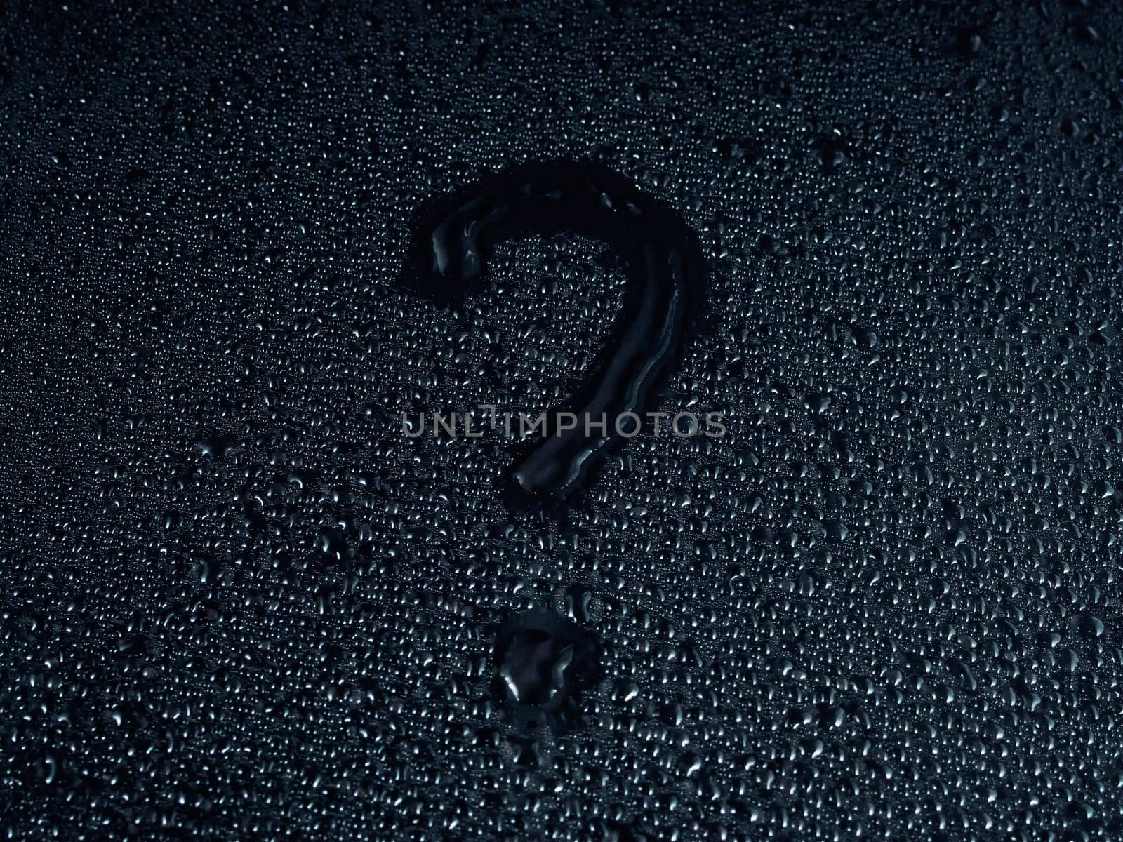 question mark written on a surface made of drops on a black background.