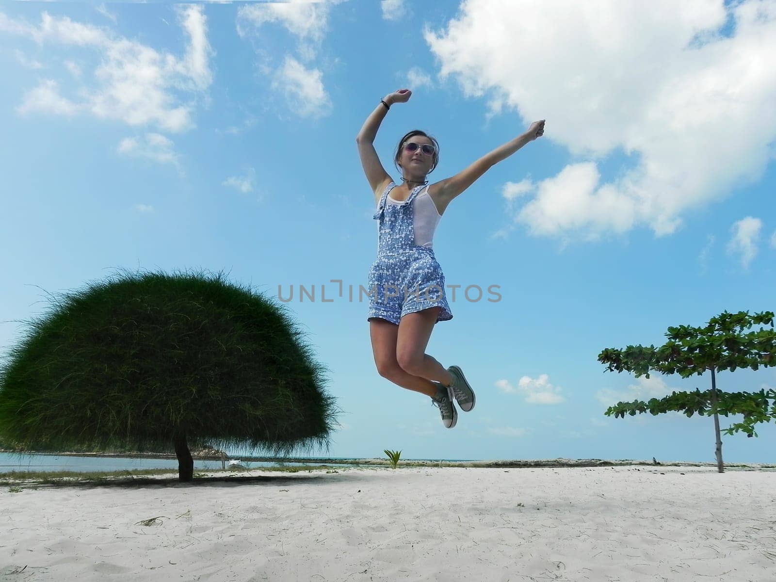 Young beautiful woman jumping in the beach