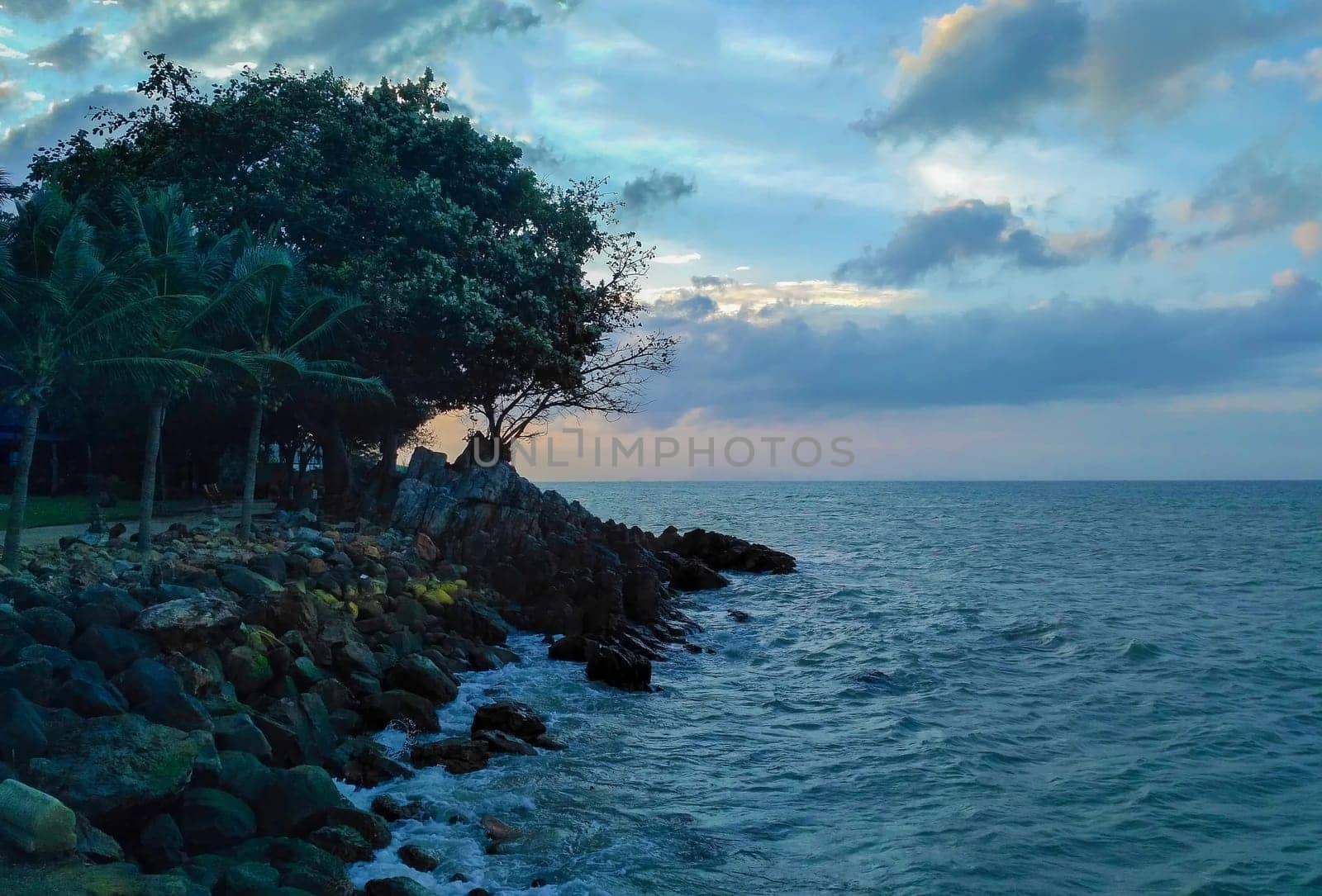 Deserted beach in blue clear sea and green trees.