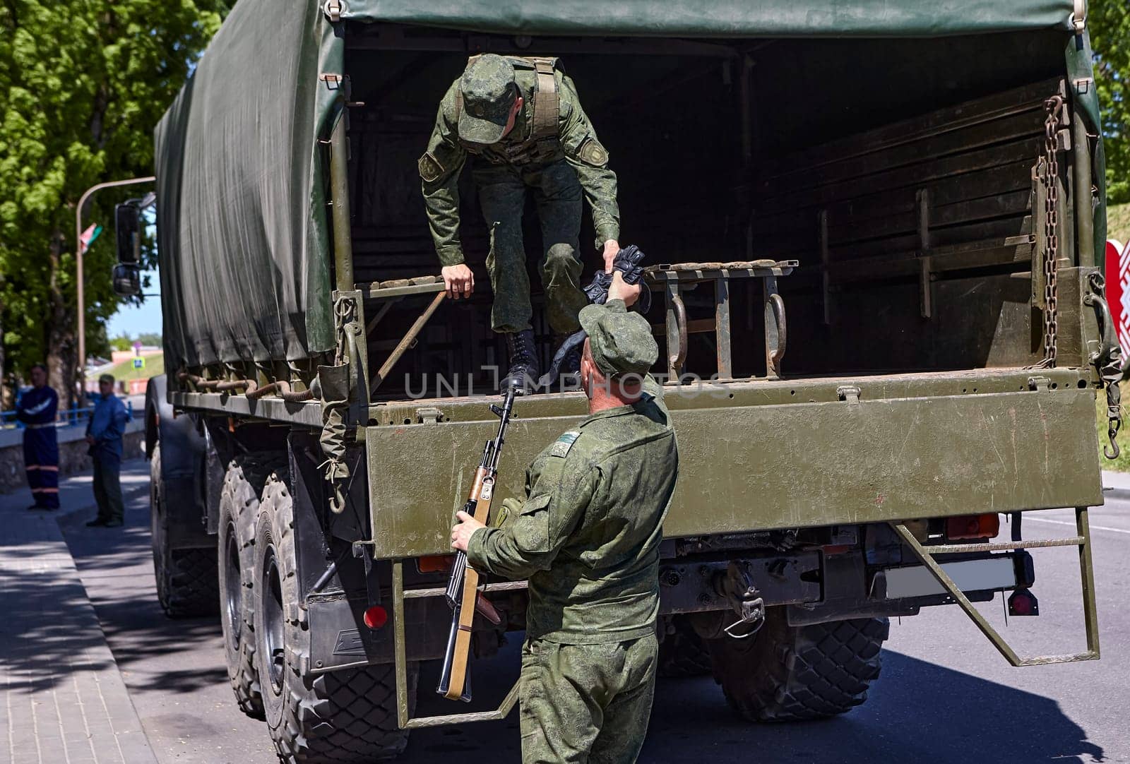 Soldiers unload firearms from a military truck. A soldier in the back of a truck.