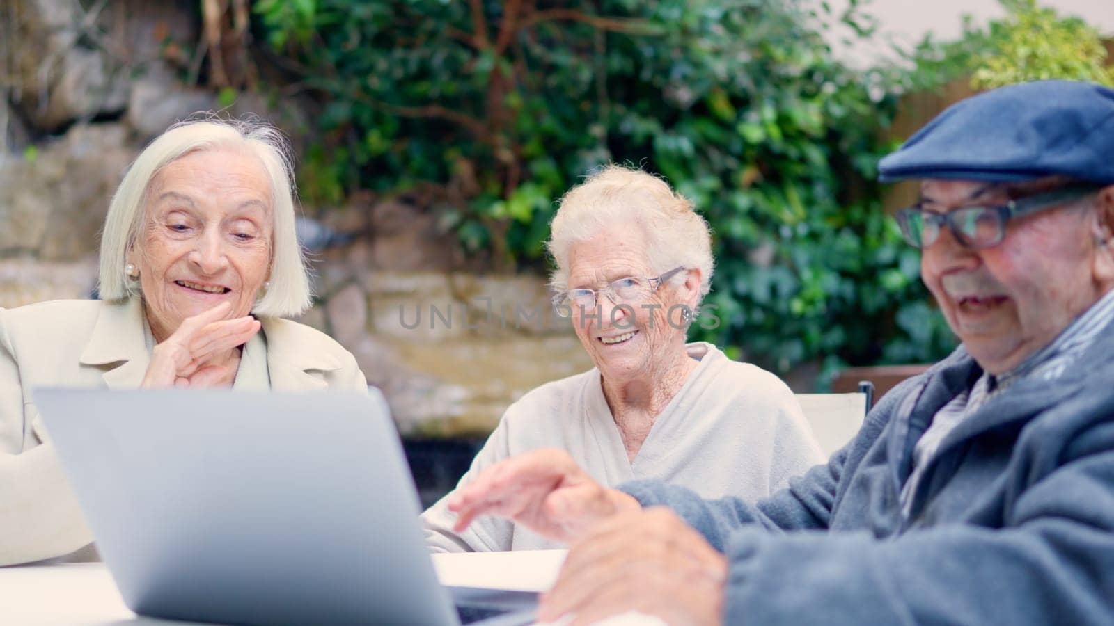 Close-up photo of seniors of a geriatric waving during a video call with laptop