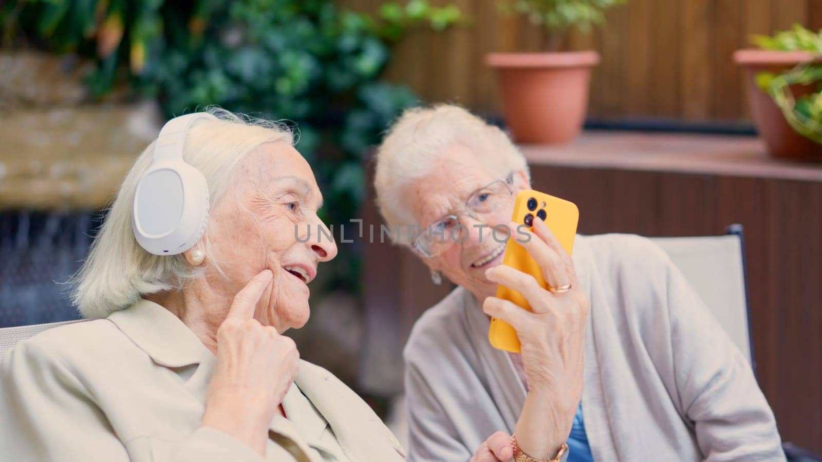 Photo of female seniors having fun with the mobile phone in a nursing home