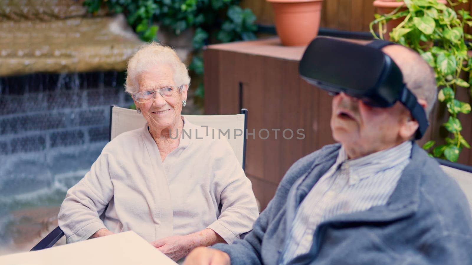 Two seniors having fun while using virtual reality goggles in the garden of a nursing home