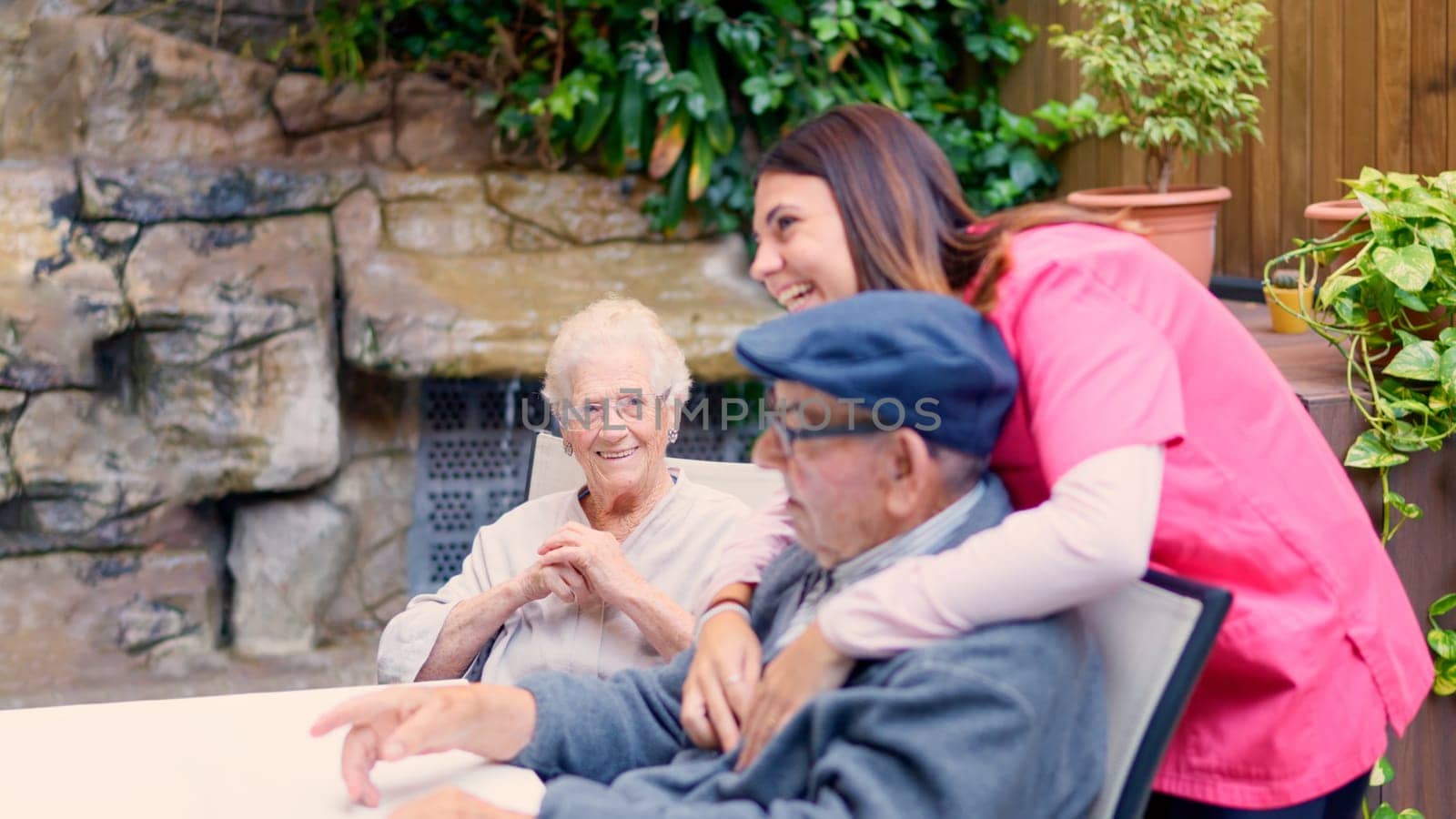 Nurse and seniors talking and laughing in the garden of geriatric