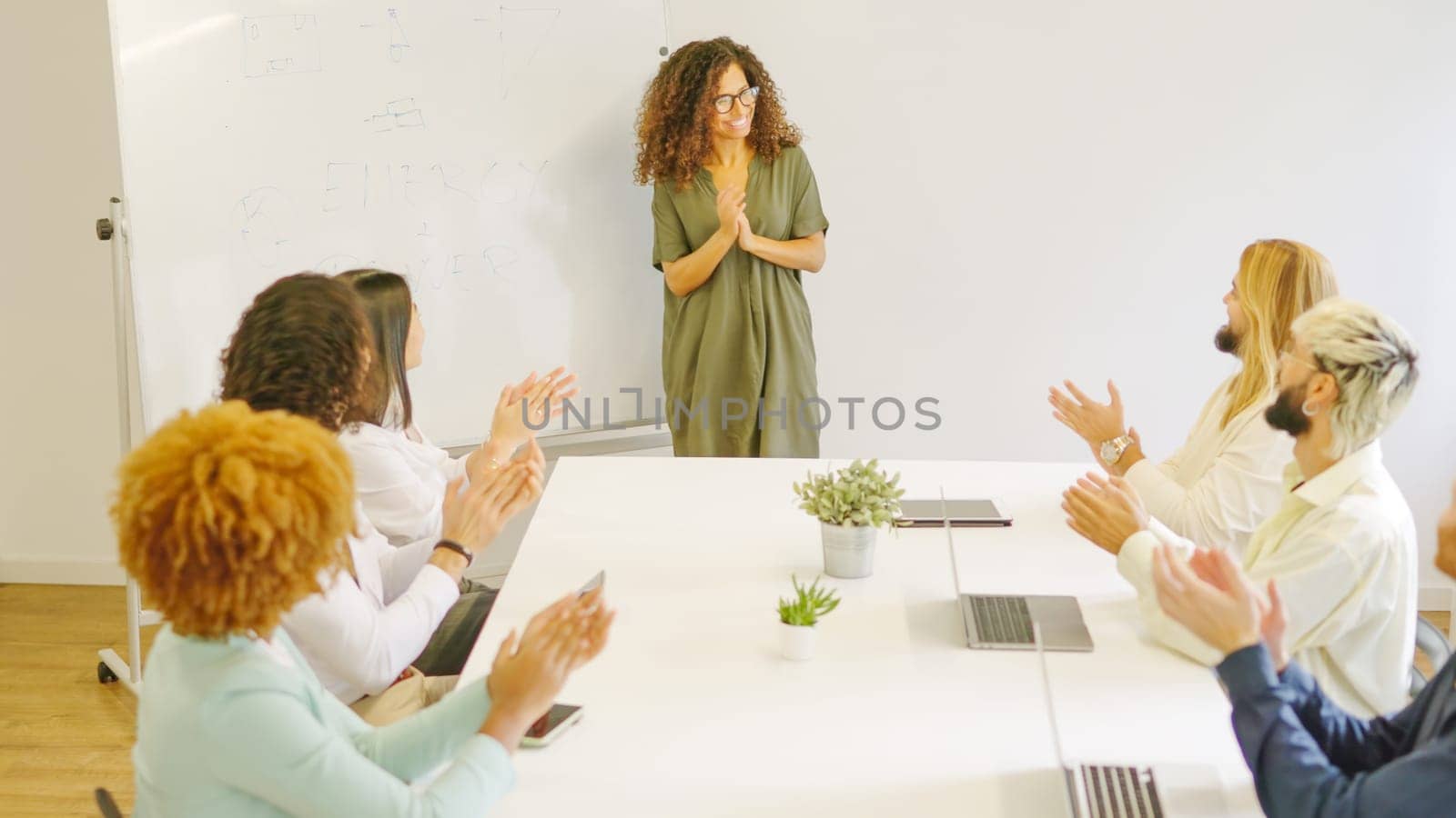 Diverse colleagues applaud a businesswoman after a presentation using white board in a meeting room