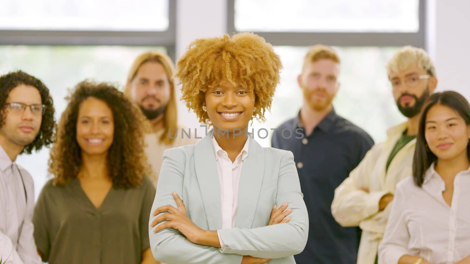 African woman leading a work team in the office standing proud and looking at camera together