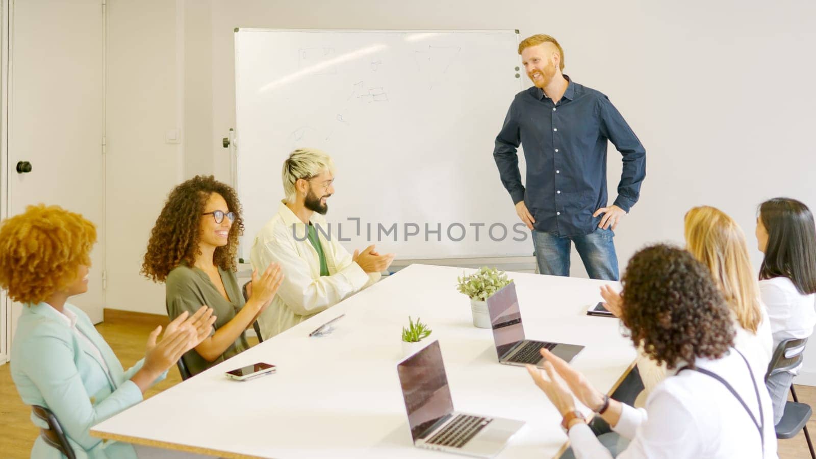 Team of coworkers applauding a man after a presentation in a meeting room
