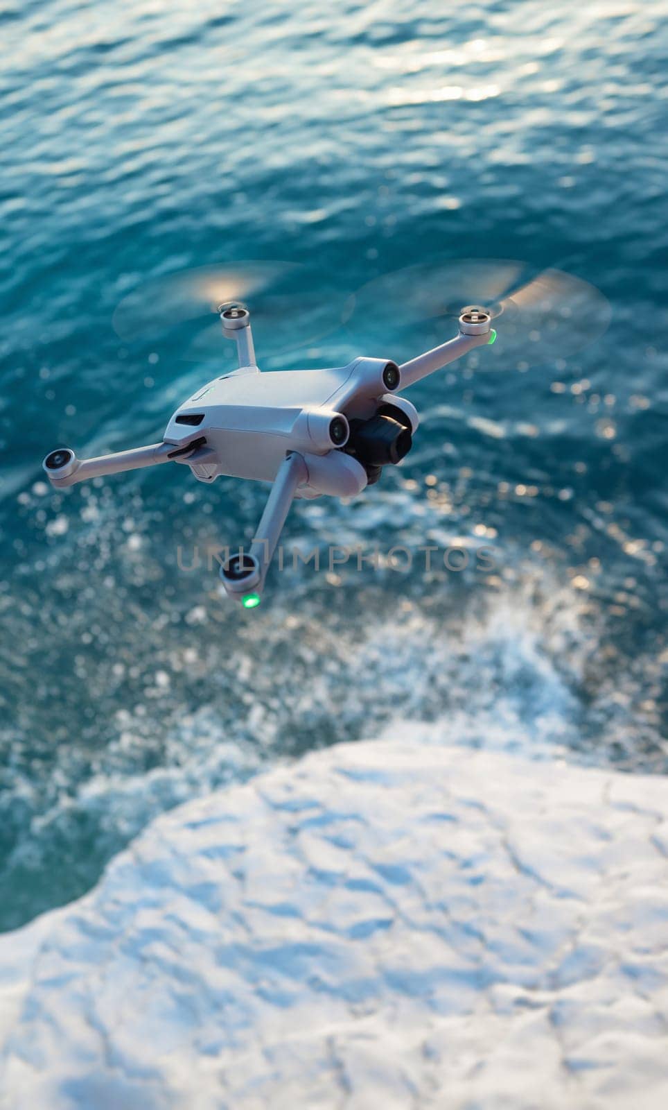 A quadcopter in flight against the background of a beautiful sea and white cliffs in sunset light