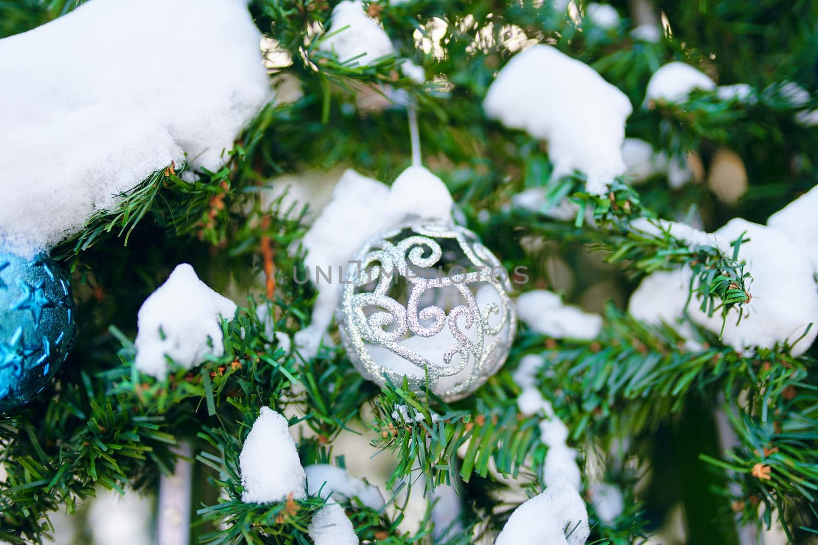 Decorated Christmas tree. Close-up of a blue bubble with snow on it hanging from a decorated Christmas tree.