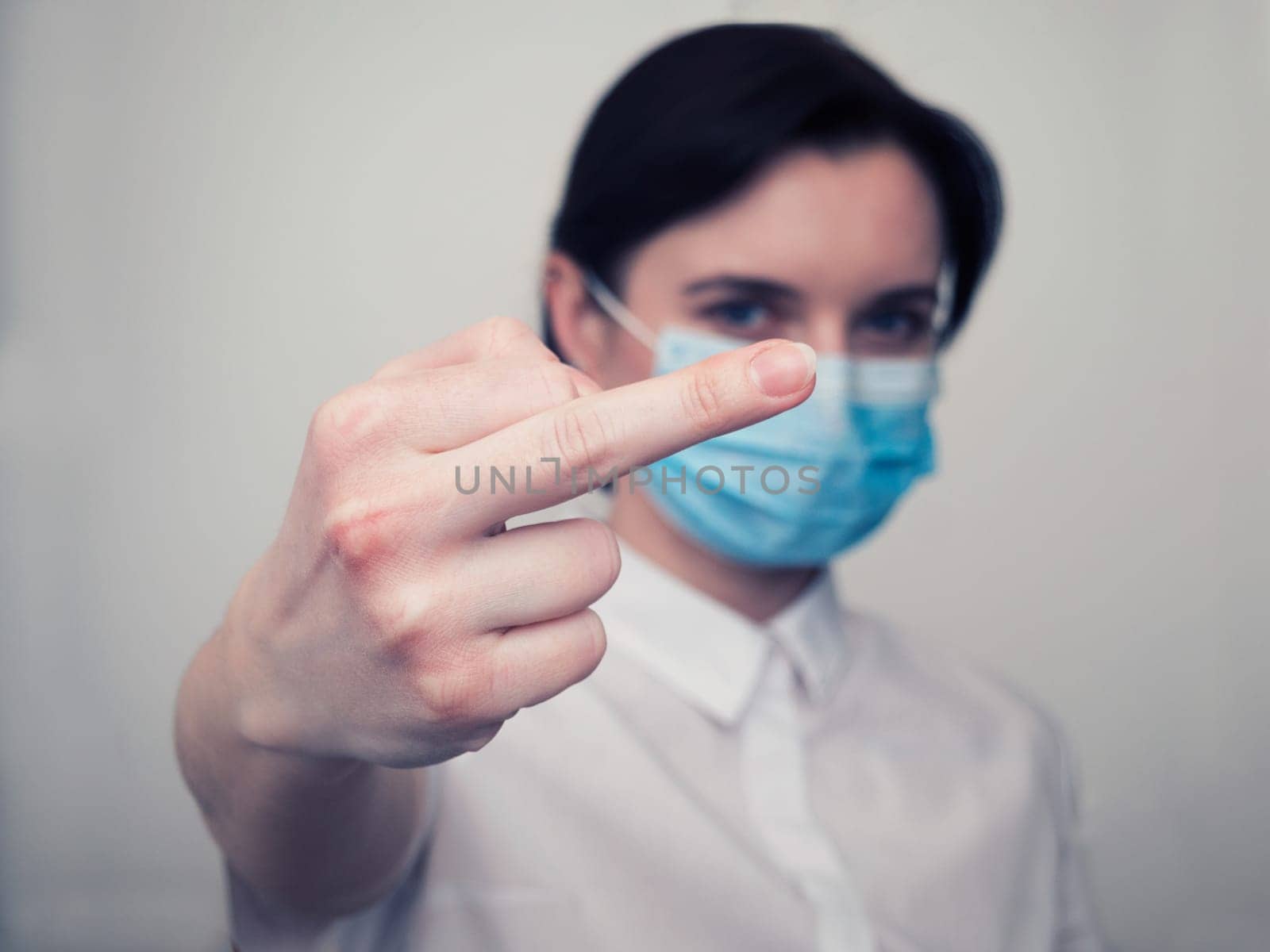 Woman with a medical mask and gloves shows by hand the symbol of the fuck off. Coronavirus concept. Fuck you corona. by Andre1ns