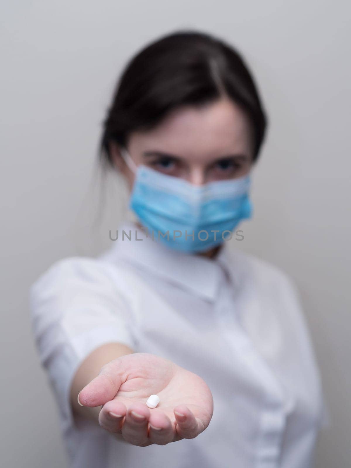 Doctor giving pills, woman in medical mask and gloves. The concept of the dose of drugs, vitamins, medical examination, coronavirus, treatment of influenza. by Andre1ns