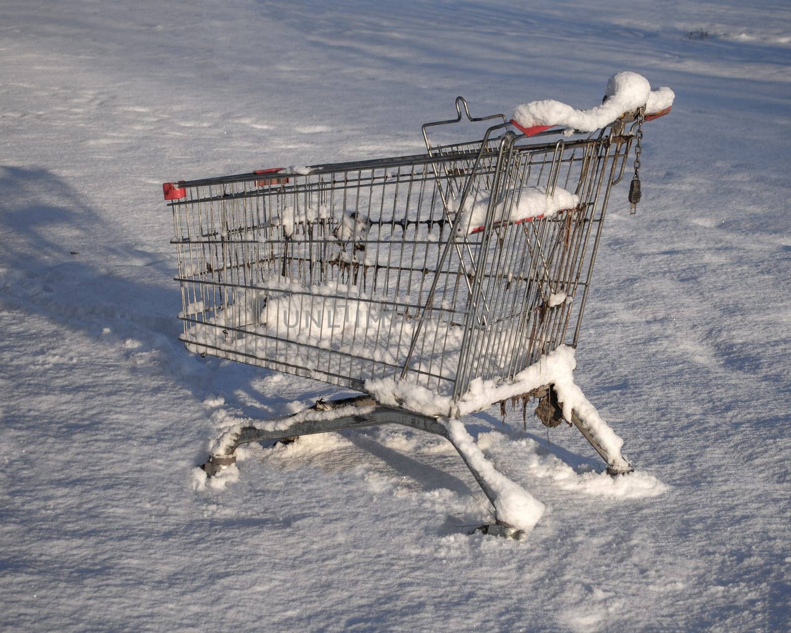 Shopping cart from the supermarket in the snow. The concept of closed stores, low demand, crisis, corontin. Consumer winter.