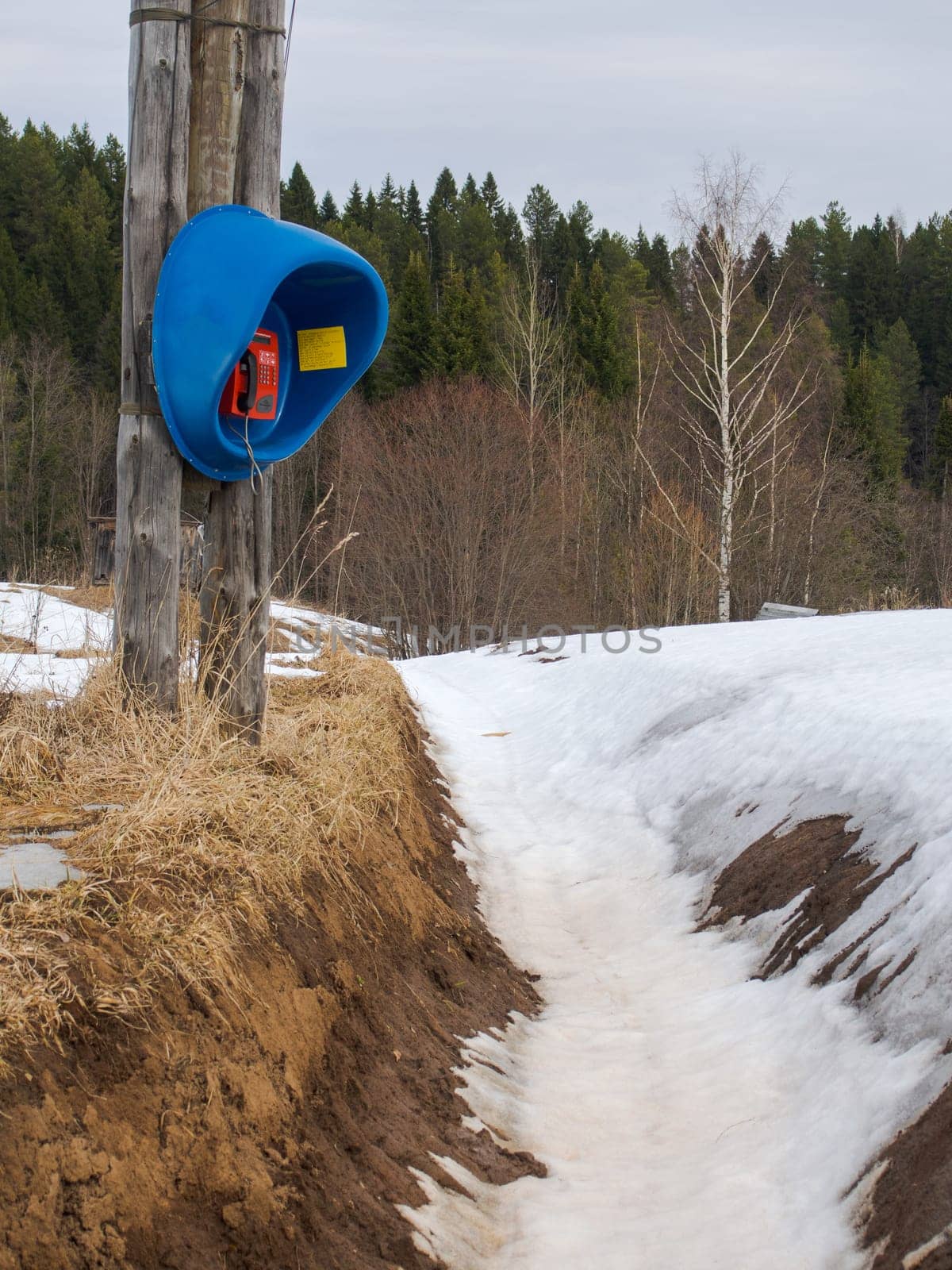 An old, forgotten, useless telephone in Siberia in the winter among the snow by the ditch.