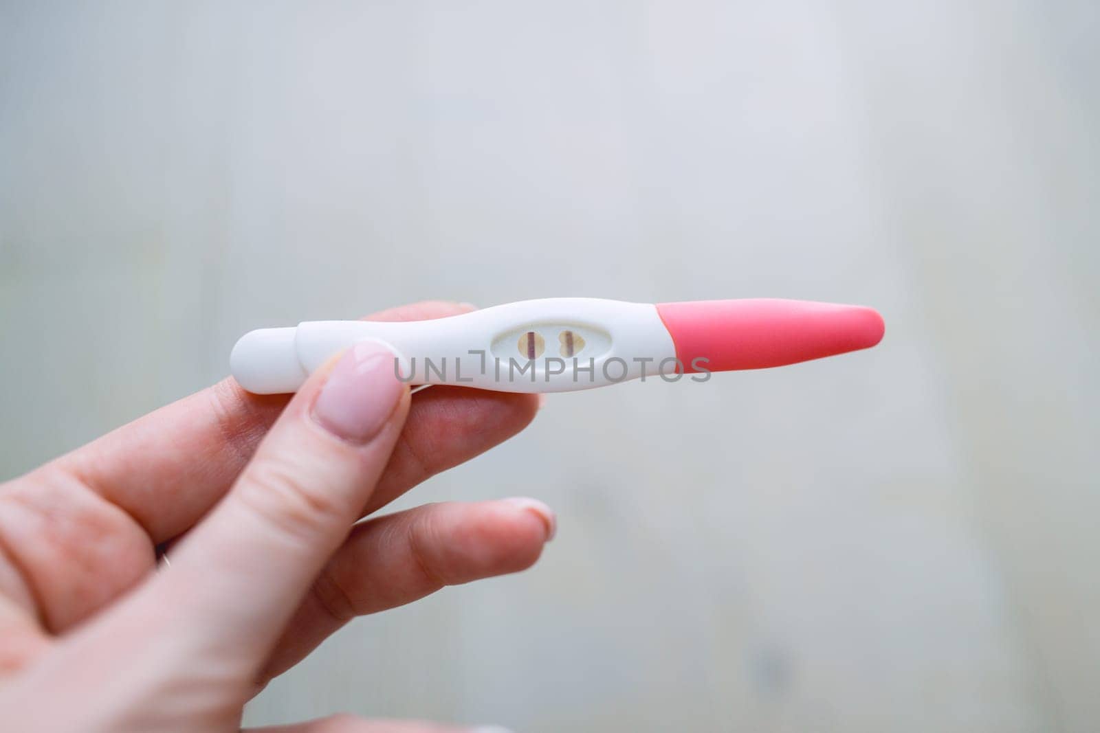 Woman hand holding positive pregnancy test with two lines on it. Pregnancy or fertility concept. High quality photo. High quality photo