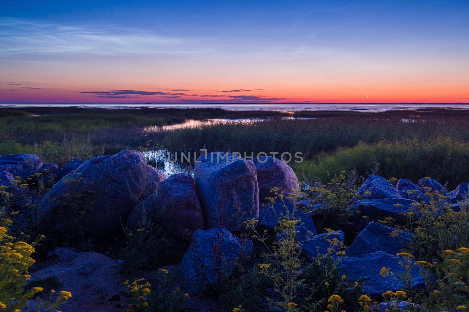 Pebble stones on the shore close up in the blurry sunset light in the distance background. by Andre1ns