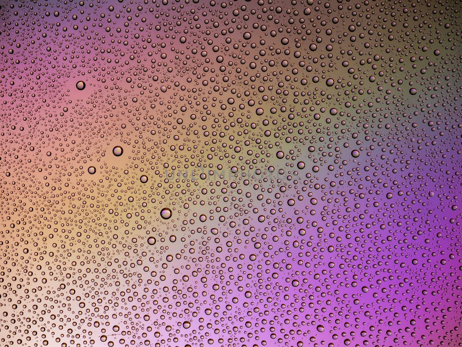 Water droplets on the glass with a colored background. Drops of water.