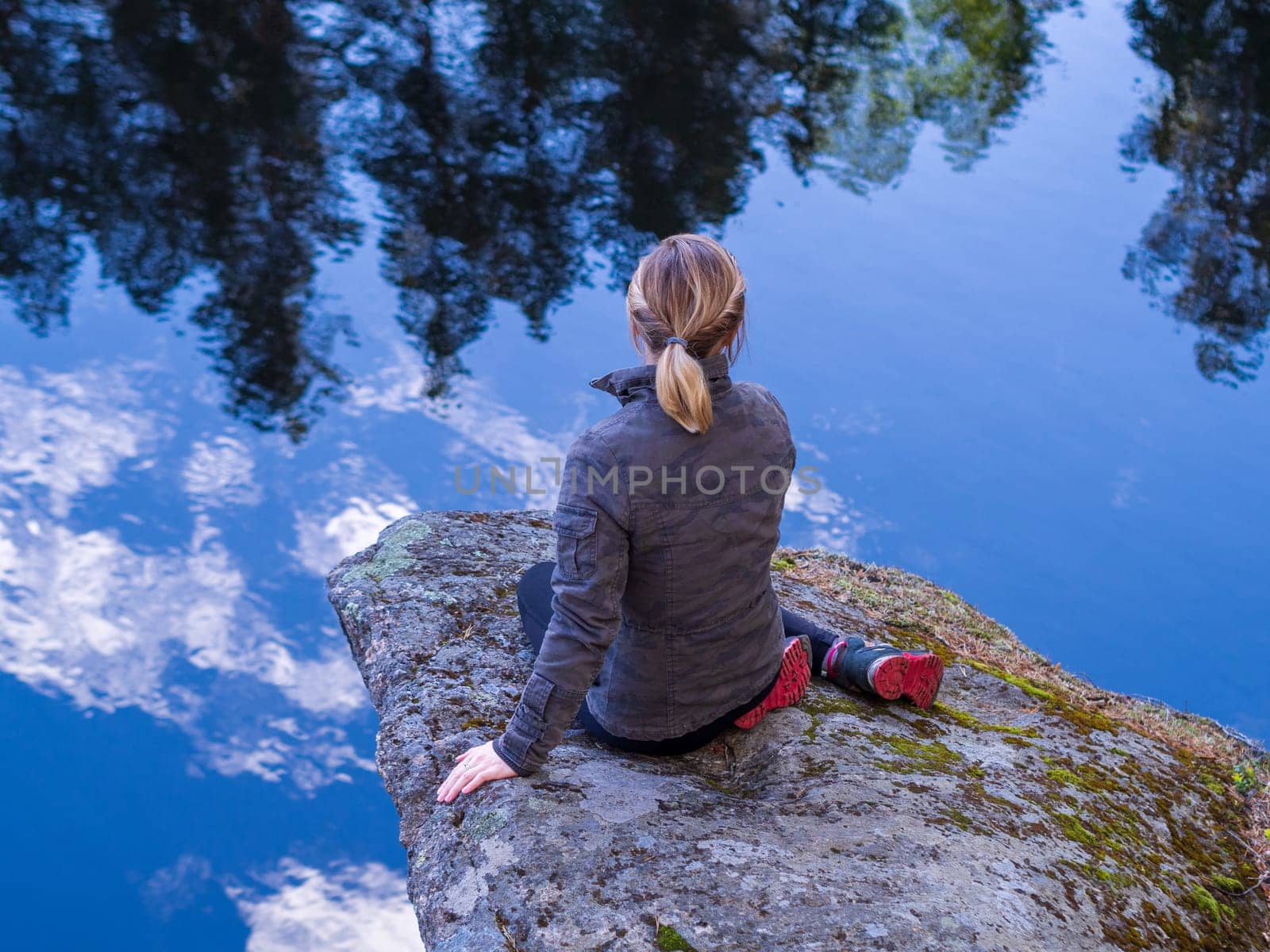 Woman sitting on a rocky ledge above the clouds