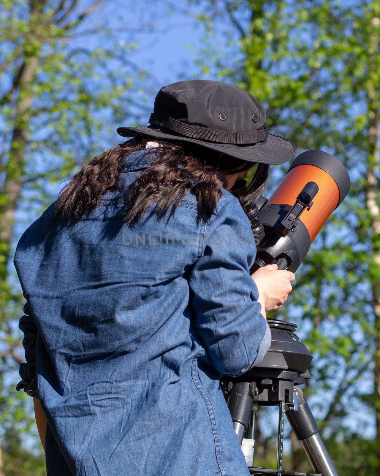 Portrait of young woman looking through the telescope on the hil