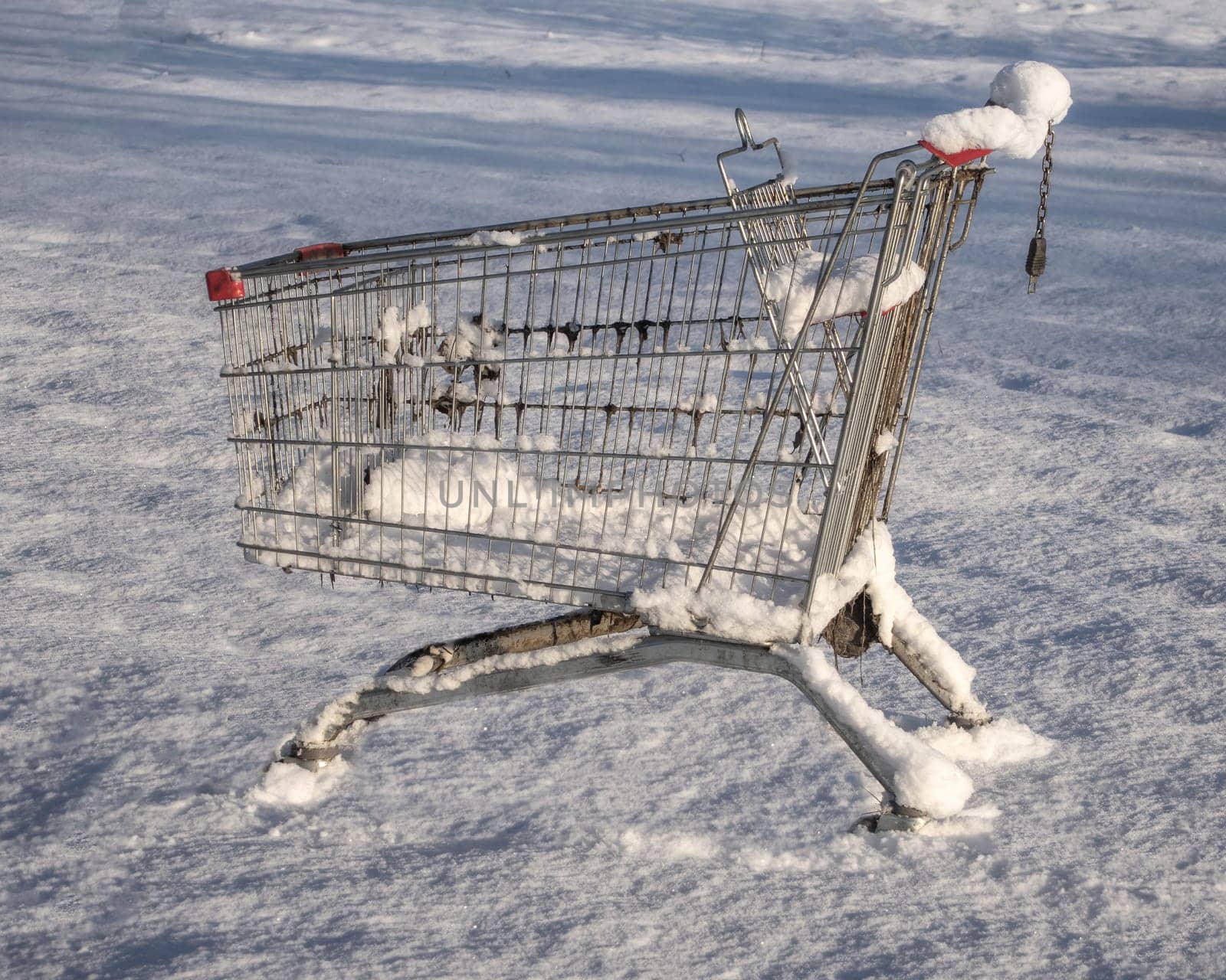 Shopping cart from the supermarket in the snow. The concept of closed stores, low demand, crisis, corontin. Consumer winter.
