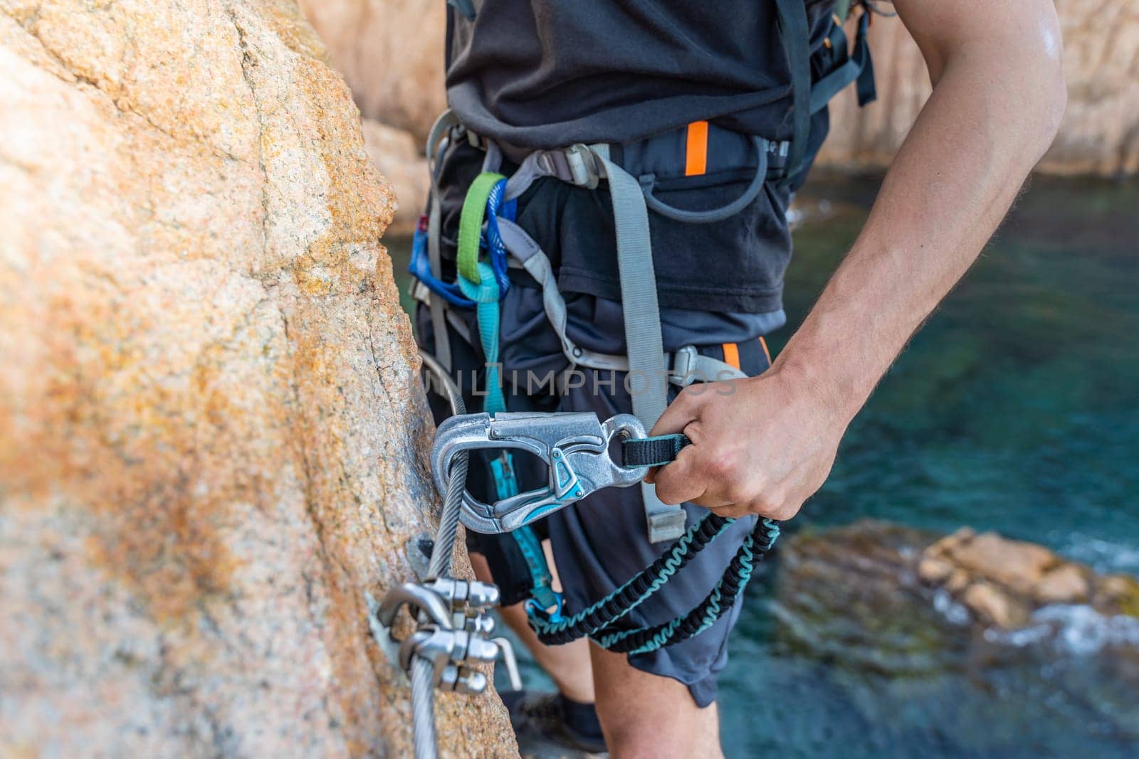 Climbing grips details young man's hand on rocks over the sea with rope and helmet. High quality photo