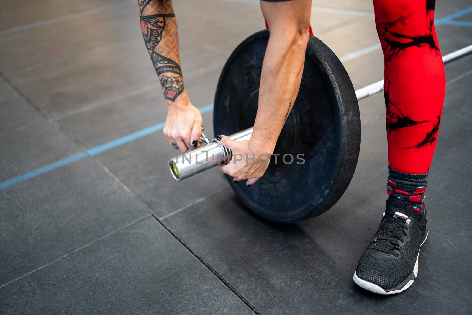 Top close-up view of a woman securing a clamp at the end of a weightlifting bar