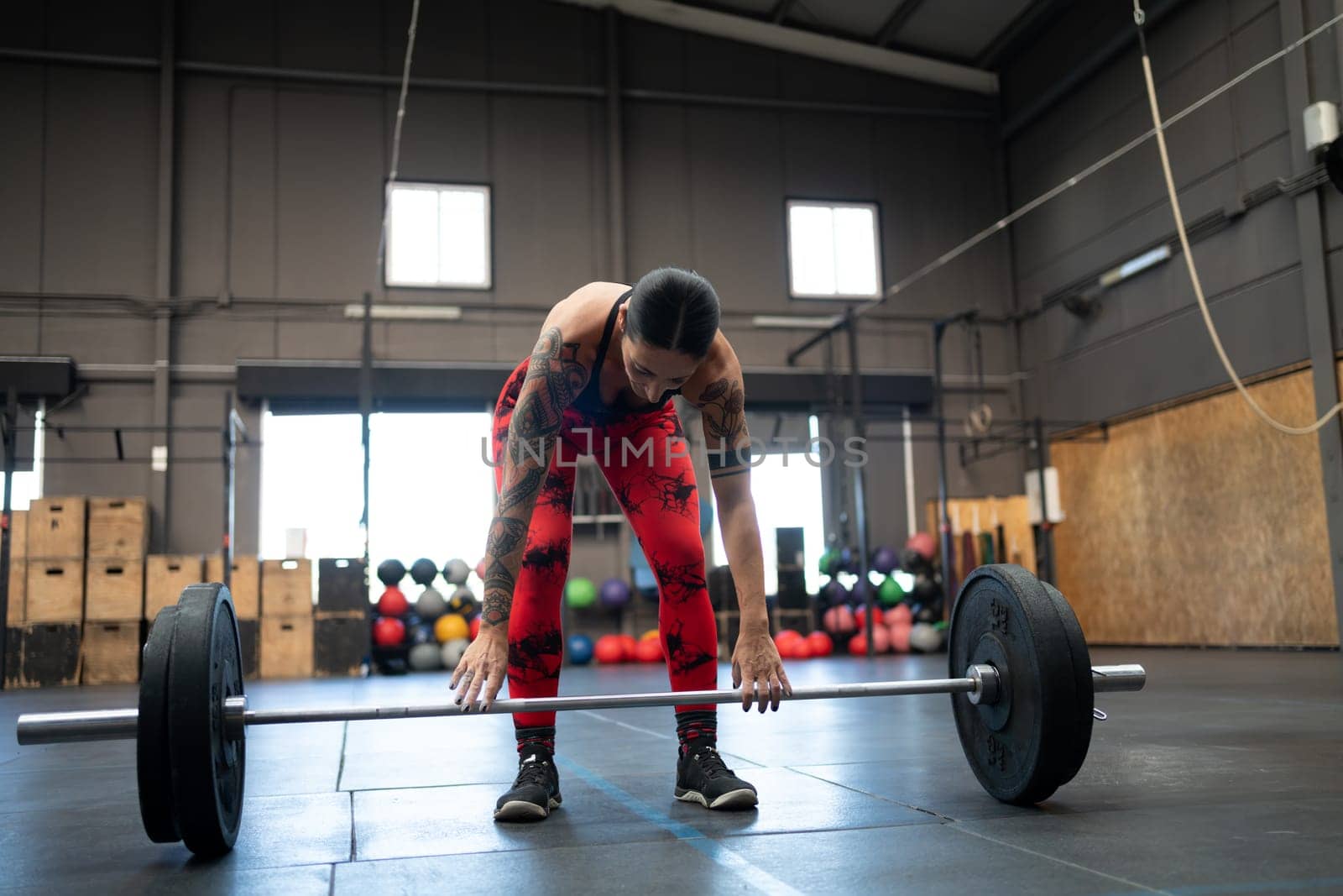 Horizontal photo with copy space of a tired strong woman weightlifting alone in a gym