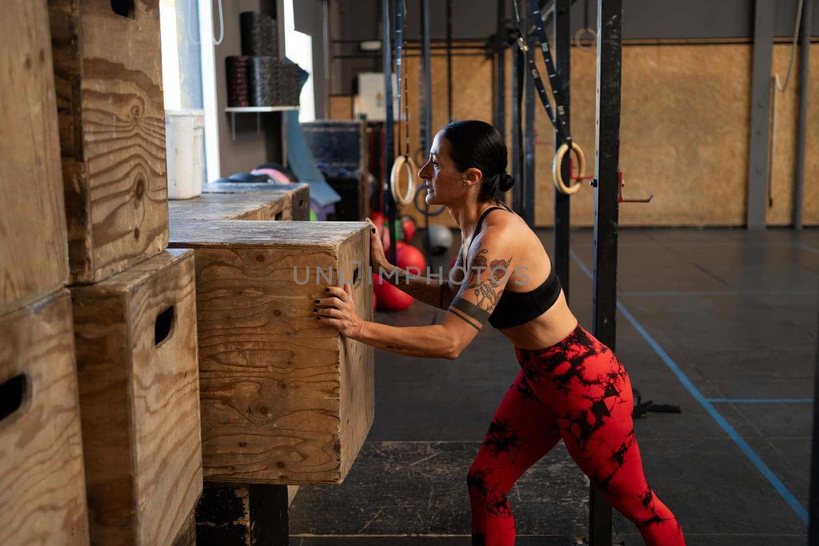 Sportive woman placing boxes in a cross training gym to maintain order