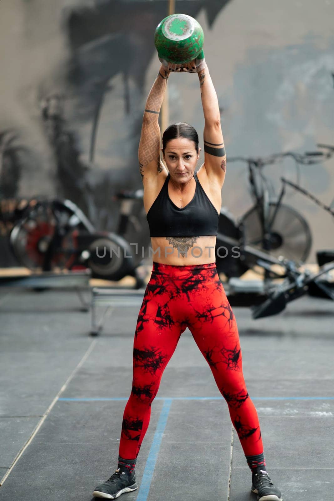 Woman lifting a kettlebell standing in a cross training gym by javiindy