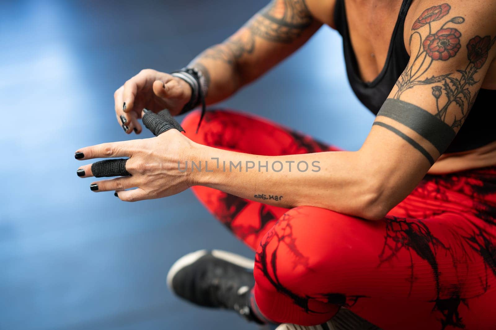 Close-up of athlete protecting her fingers with tape while sitting in the gym