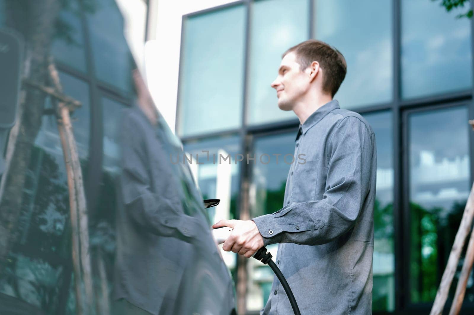 Young man travel with EV electric car in green sustainable city innards by biancoblue