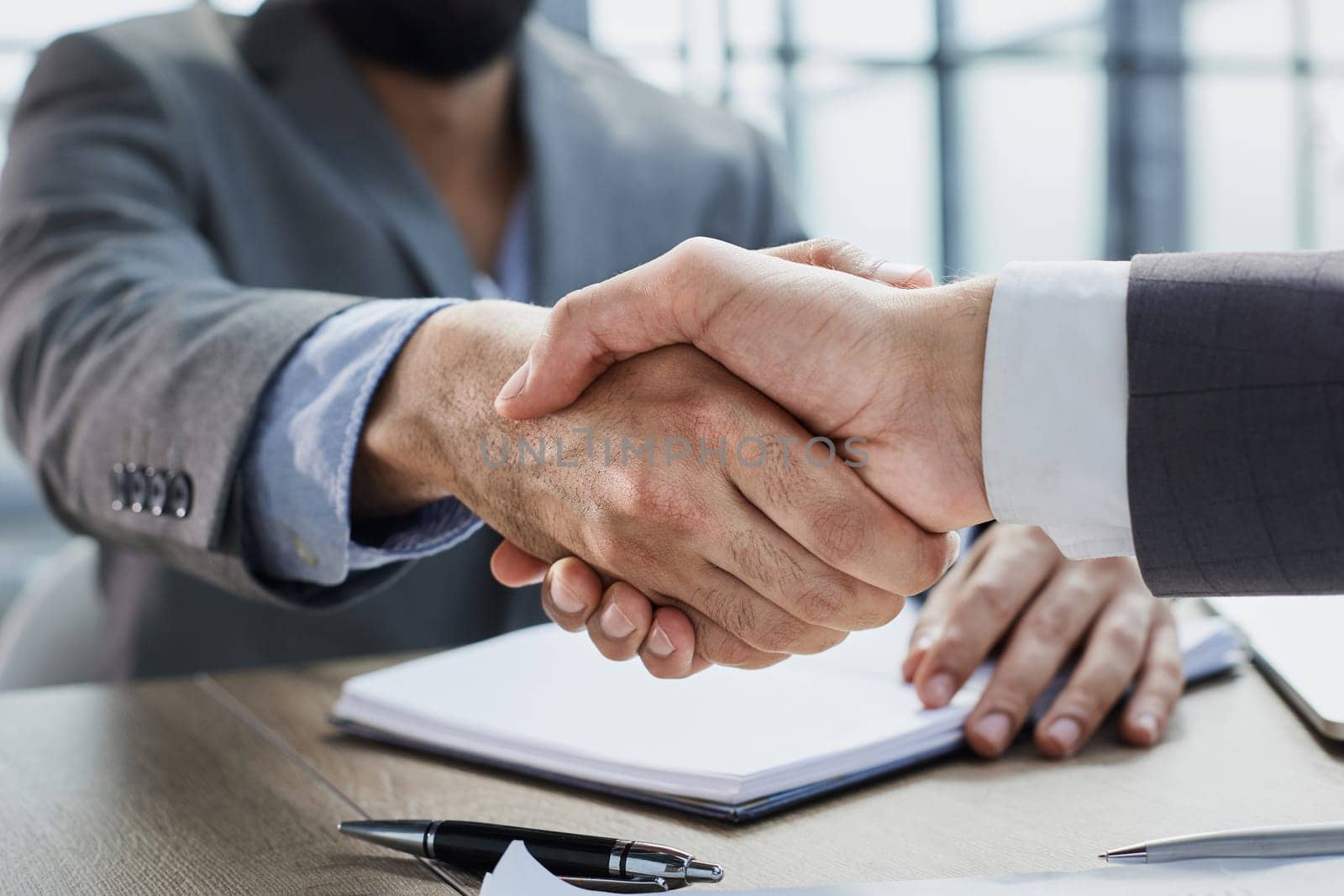handshake in the office of two businessmen at the table by Prosto