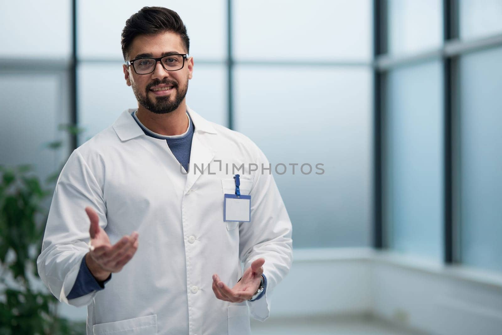 The doctor, an average man, makes a hand gesture inviting patients. by Prosto