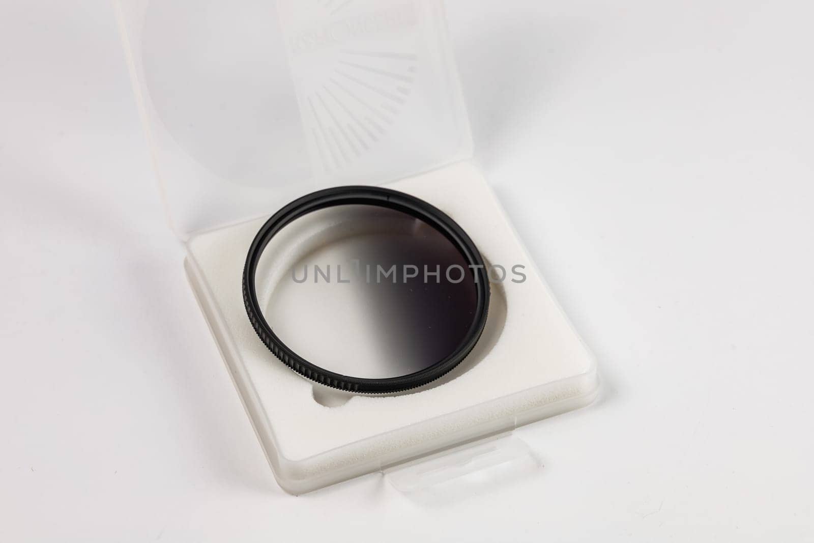Circle graduated filter ND16 lying on the foam of white transparent box