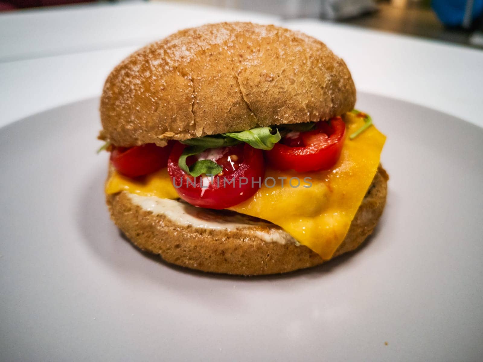 Cheeseburger with gluten-free bun and cherry tomatoes and salad on small gray plate