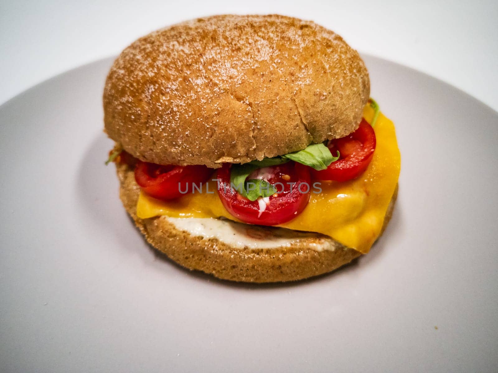 Cheeseburger with gluten-free bun and cherry tomatoes and salad on small gray plate by Wierzchu