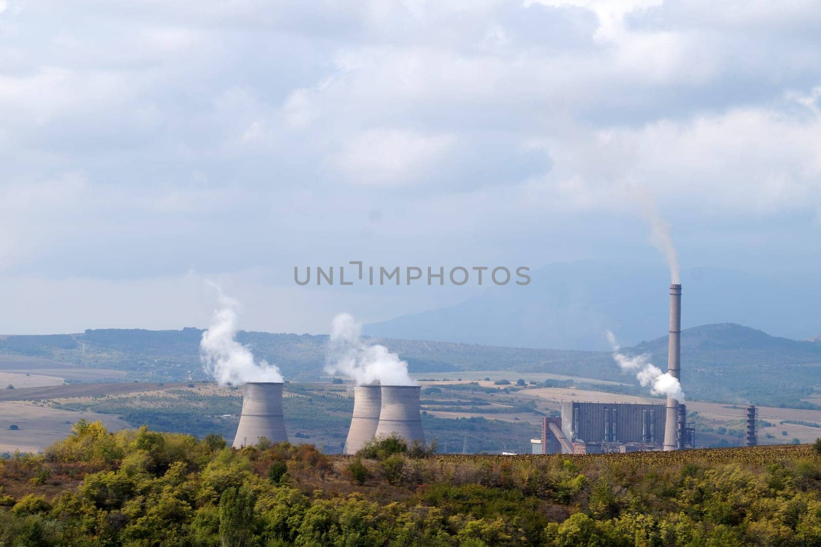 thermal power plant with smoking pipes against the backdrop of mountains by Annado
