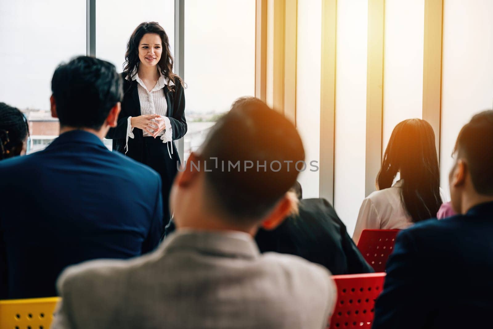 Office meeting with a diverse group of businesspeople. Seated colleagues converse, while male and female managers stand, facilitating a dynamic exchange of ideas. by Sorapop