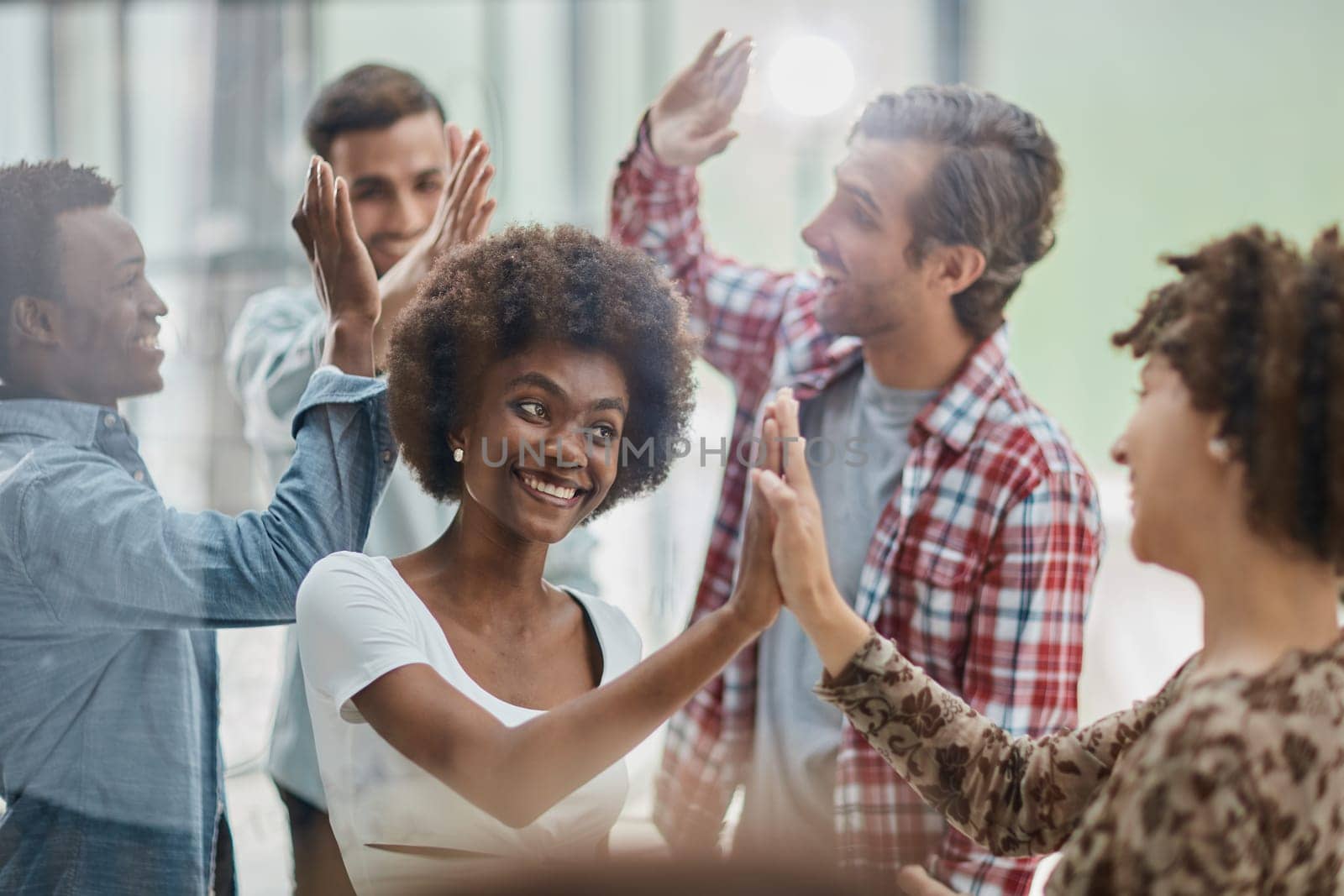 Excited multiracial employees give high five engaged in teambuilding activity in office together